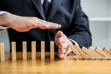 Ahşap oyun stratejisi, iş adamı el durdurma ahşap domino etkisi sürekli devrildi ya da tehlikeye düşen ve koruma, strateji ve iş için başarılı müdahale kavramı.