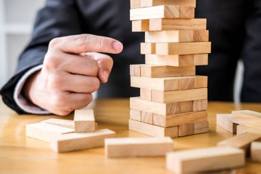 Alternatif risk planı ve büyüme kar iş, Genç zeki işadamı ahşap oyun oynamak için bir strateji executive sipariş ahşap blok kule üzerinde eller.