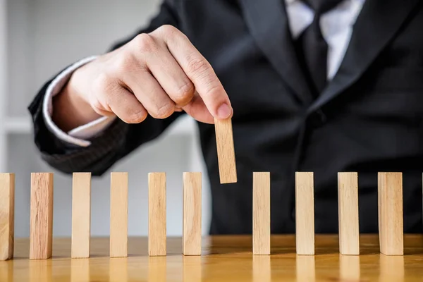 Wooden game strategy, Risk and strategy in business, Close up of businessman hand gambling placing wooden block on a line of domino.