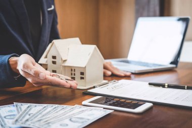 Emlakçı Satış Müdürü, kira kontratı ve konut sigortası için ipotek kredisi teklifiyle ilgili satış sözleşmesini imzaladıktan sonra müşterinin dosyalama anahtarlarını tutuyor..