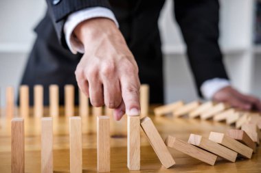 Ahşap oyun stratejisi, iş adamı el durdurma düşen tahta domino etkisi sürekli devrildi veya risk, strateji ve iş için başarılı müdahale kavramı.