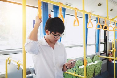 Küçük Asya adam müzik Smartphone cep telefonu ile gülümseme mutlu, ulaşım, turizm ve road trip kavramı ile süre giden bir otobüse duran gezgin.
