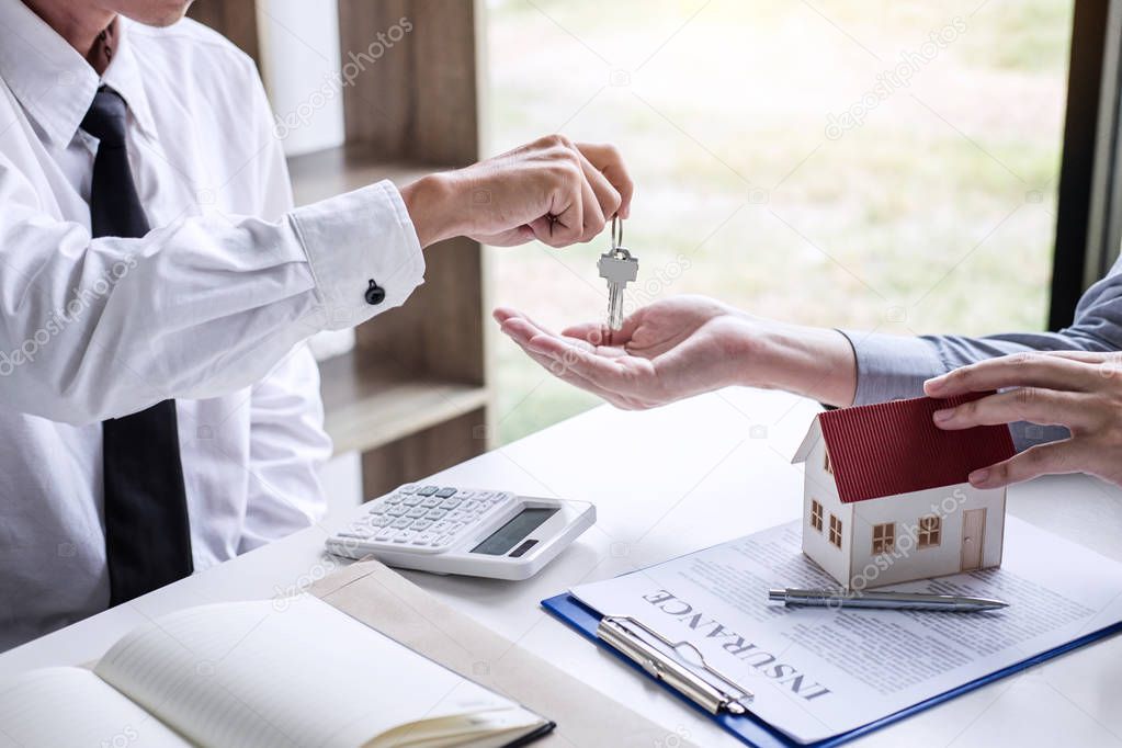 Real estate Sales manager giving keys to customer after signing rental lease contract of sale purchase agreement, concerning mortgage loan offer for and house insurance.