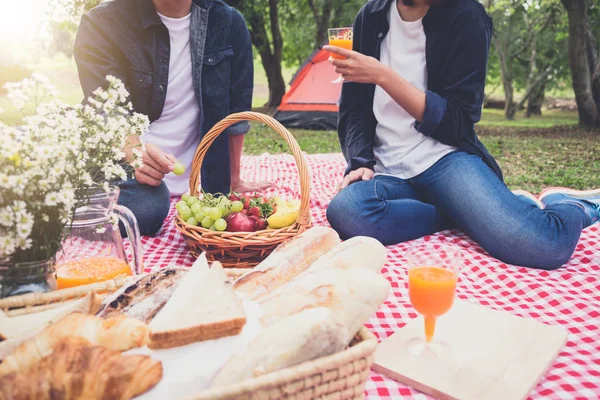 Couple in love drink a orange juice and fruits on summer picnic, leisure, holidays, eating, people and relaxation concept.