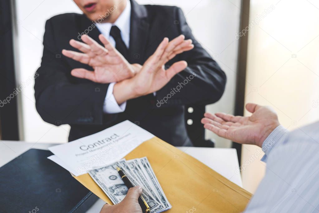 Bribery and corruption concept, senior businessman manager refusing receive money in the envelope to agreement contract, A bribe in the form of dollar bills.