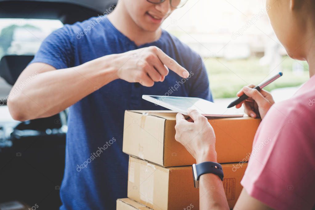 Woman customer appending signature in digital tablet and receiving a cardboard boxes parcel from delivery service courier, Home delivery service and working with service mind.
