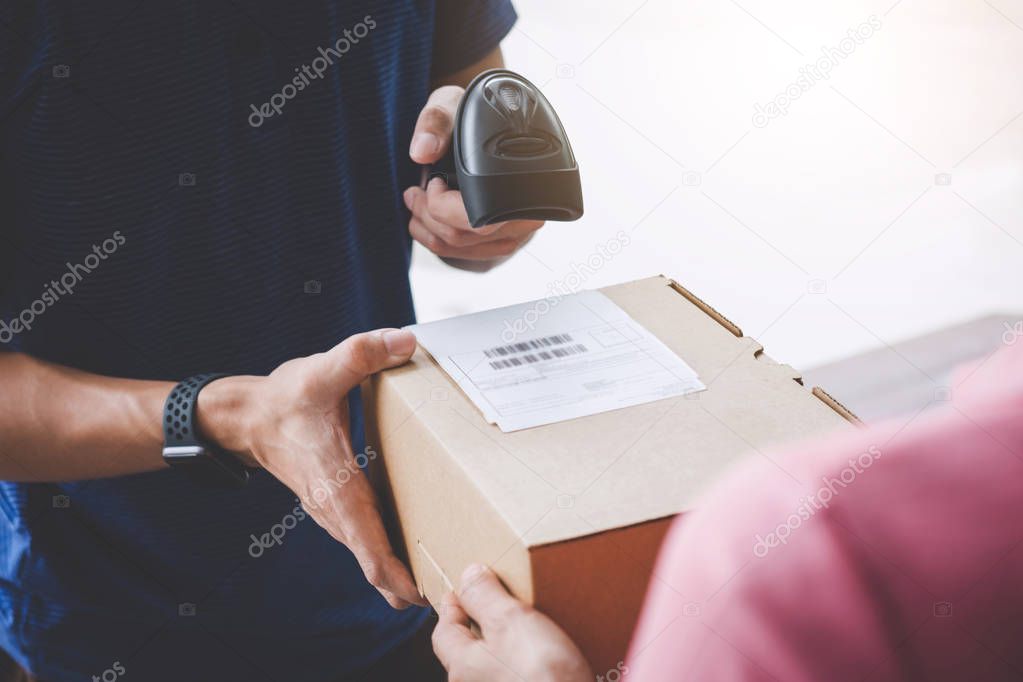 Home delivery service and working service mind, Woman customer hand receiving a cardboard boxes parcel from service courier and deliveryman scan barcode to confirm delivery.