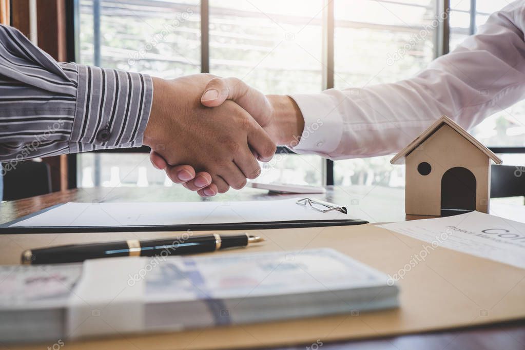 Real estate broker agent and customer shaking hands after signing contract documents for realty purchase, Bank employees congratulate, Concept mortgage loan approval.
