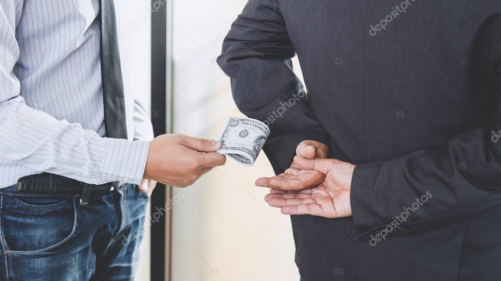 Bribery and corruption concept, bribe in the form of dollar bills, Businessman giving money while making deal to agreement.