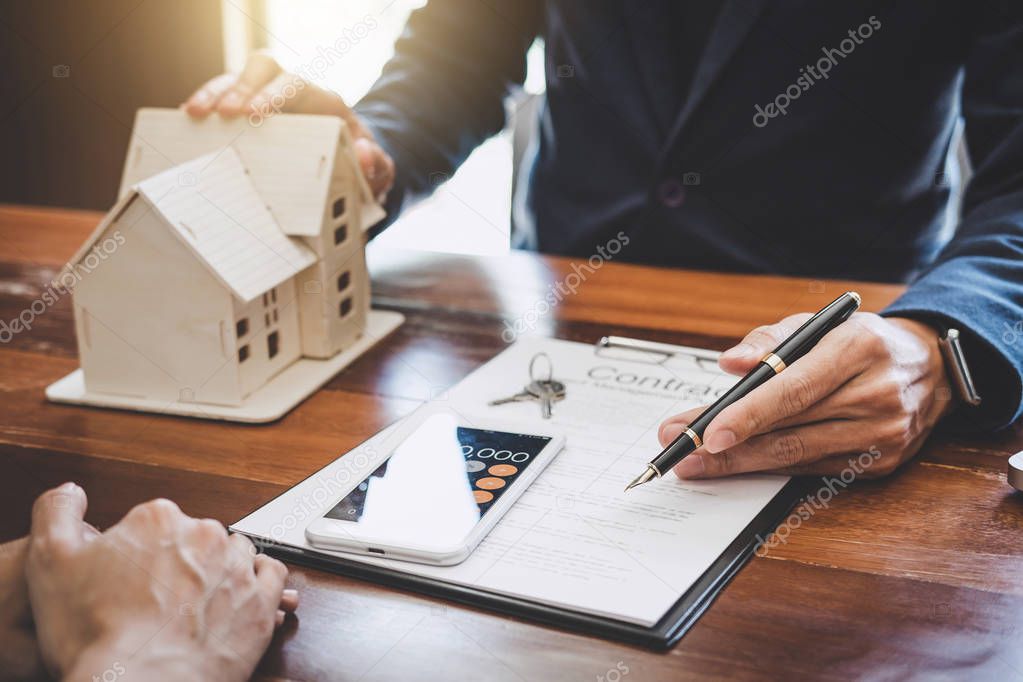 Real estate broker agent presenting and consult to customer to decision making sign insurance form agreement, home model, concerning mortgage loan offer for and house insurance.