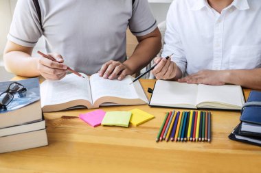 Eğitim, öğretim, öğrenme, teknoloji ve insan kavramı. İki liseli ya da sınıf arkadaşı arkadaşlarıyla birlikte sınıf ödevlerini, ders kitaplarını ve arkadaşlarıyla birlikte yapıyor..