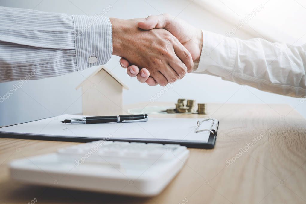 Real estate broker agent and customer shaking hands after signing contract documents for ownership realty purchase, Concept mortgage loan approval.