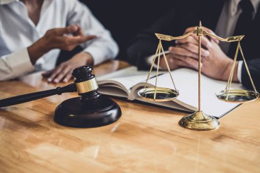 Mahkemede çalışan erkek avukat veya avukat, emlak, hukuk ve hukuk hizmetleri kavramının sözleşme belgeleriyle istişarede bulunarak müvekkilleriyle görüşür..