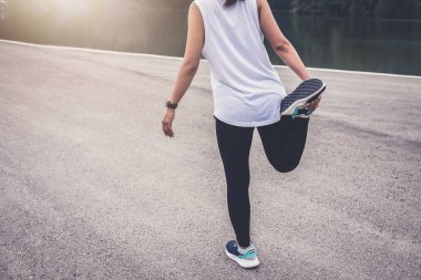 Atlet kadının bazı germe egzersizleri bacaklar açık çalıştırmadan önce yapması.