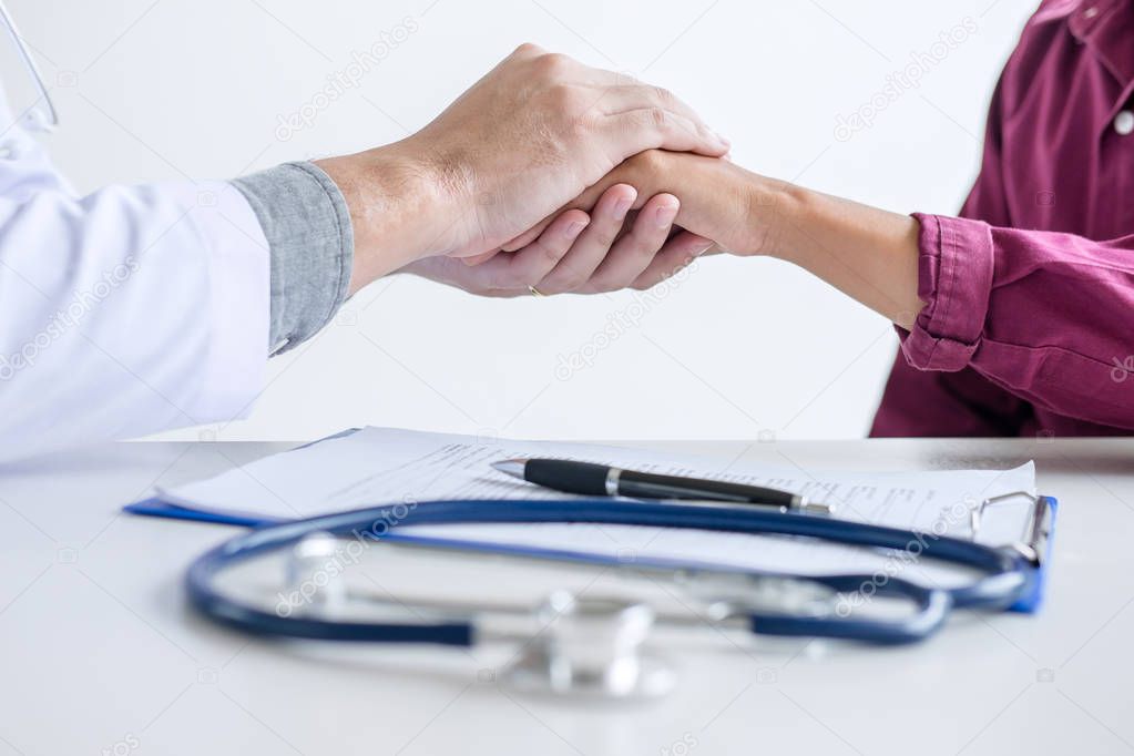 Doctor touching patient hand for encouragement and empathy on the hospital, cheering and support patient, medical examination, trust and ethics.