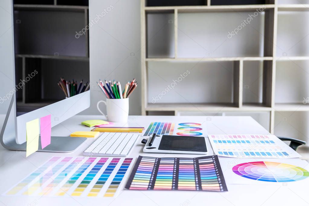 Modern office workplace with tablet, Graphic designer and color swatch samples at workplace.