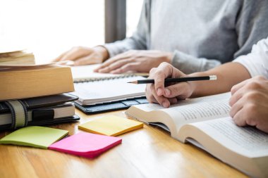 Lise öğretmeni ya da üniversite öğrenci grubu kütüphanede oturmuş ders çalışıyor, ödev yapıyor ve ders çalışıyor giriş, eğitim, öğretim, öğrenim konseptine hazırlanıyor..