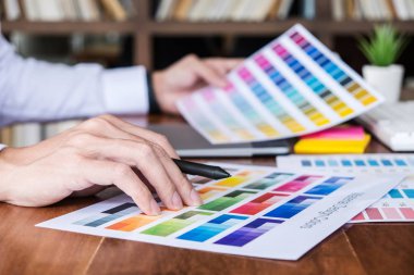 İş yerinde iş araçları ve aksesuarlarıyla renk seçimi ve grafik tableti üzerinde çalışan erkek yaratıcı grafik tasarımcı resmi.