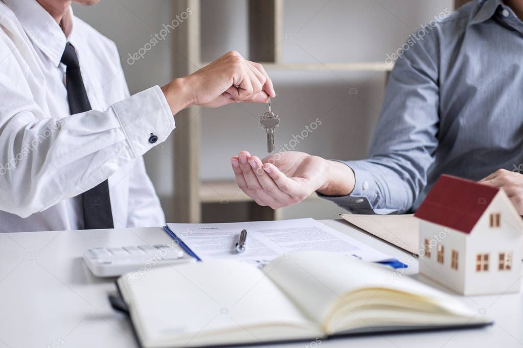 Real estate Sales manager giving keys to customer after signing rental lease contract of sale purchase agreement, concerning mortgage loan offer for and house insurance.
