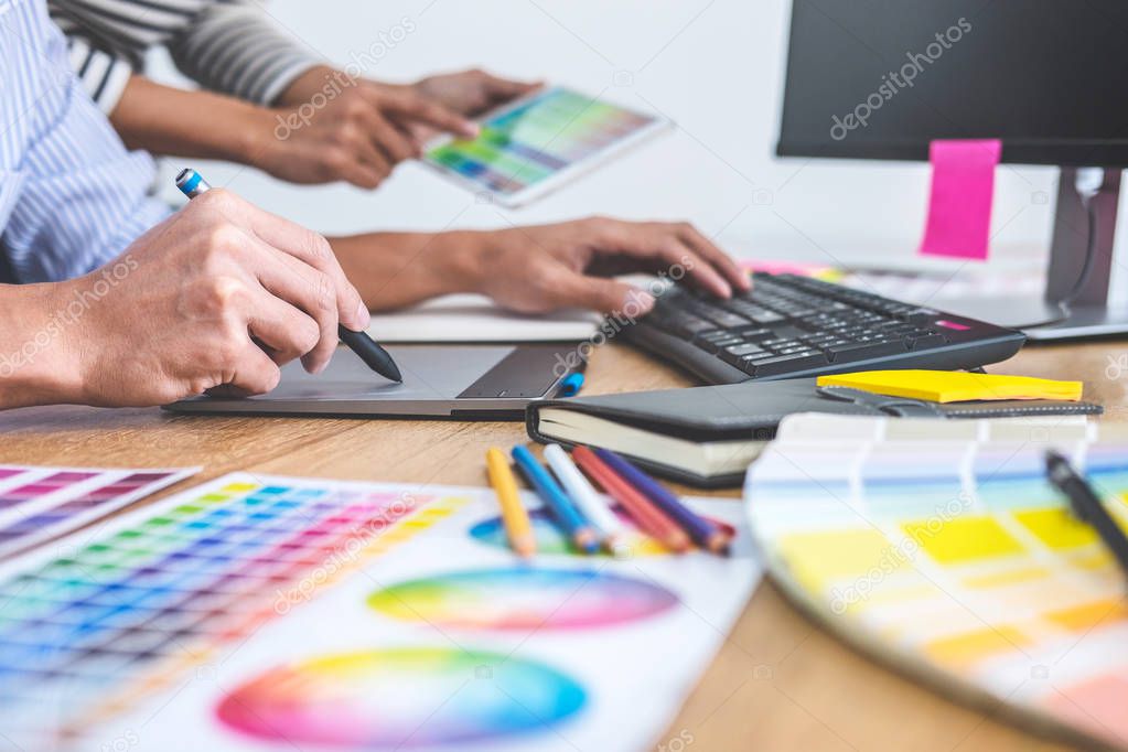 Two colleagues creative graphic designer working on color selection and drawing on graphics tablet at workplace, Color swatch samples chart for selection coloring.