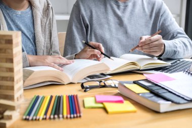 Eğitim, öğretim, öğrenme, teknoloji ve insan kavramı. İki liseli ya da sınıf arkadaşı arkadaşlarıyla birlikte sınıf ödevlerini, ders kitaplarını ve arkadaşlarıyla birlikte yapıyor..