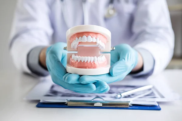 男性の医師または歯科医師の患者の歯の 線フィルム モデルおよび歯科の職場で歯科治療と分析歯の疾患で使用される機器の操作 — ストック写真