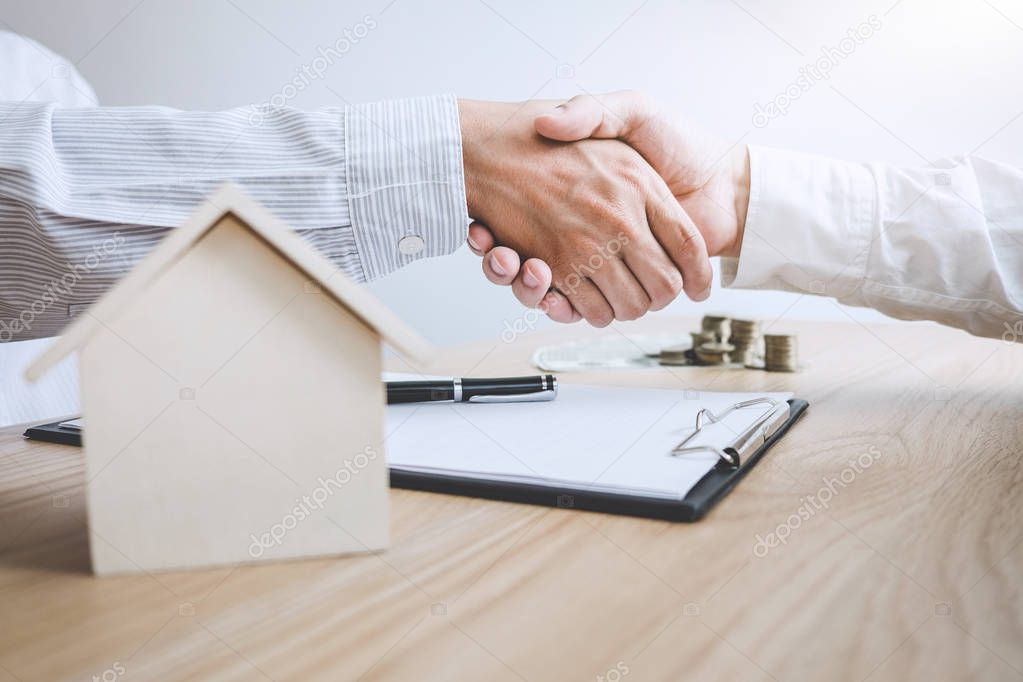Real estate broker agent and customer shaking hands after signing contract documents for ownership realty purchase, Concept mortgage loan approval.