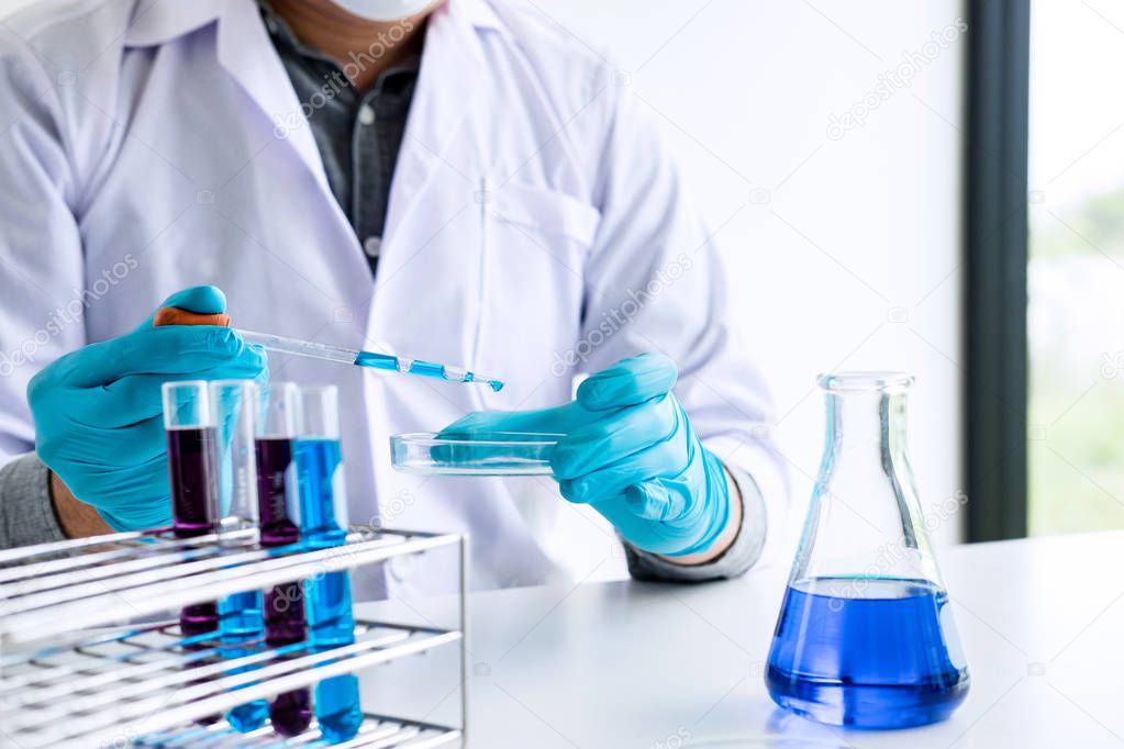 Biochemistry laboratory research, Chemist is analyzing sample in laboratory with equipment and science experiments glassware containing chemical liquid.