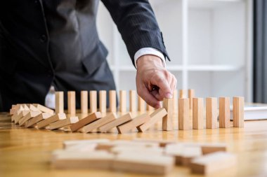 Ahşap oyun stratejisi, iş adamı el durdurma düşen tahta domino etkisi sürekli devrildi veya risk, strateji ve iş için başarılı müdahale kavramı.