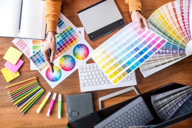 İş yerinde iş araçları ve aksesuarlarıyla renk seçimi ve grafik tableti üzerinde çalışan kadın yaratıcı grafik tasarımcı resmi, üst görünüm çalışma alanı.