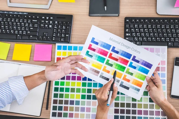 Young creative team having a meeting in creative office, Architectural drawing with work tools and accessories, Color swatch samples chart for selection coloring.