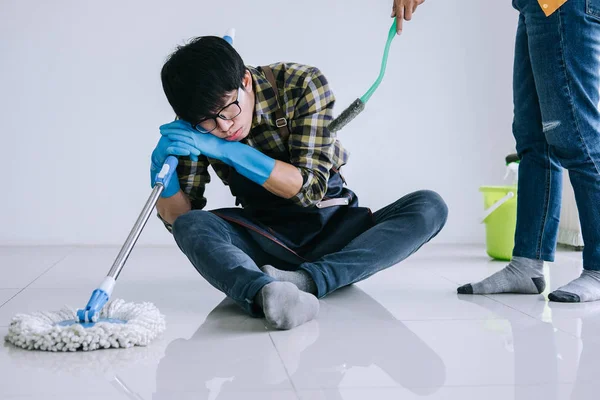 夫の家事 家の床を掃除しながらモップを使用してほこりを拭いて青いゴム手袋で疲れた男をクリーニング — ストック写真