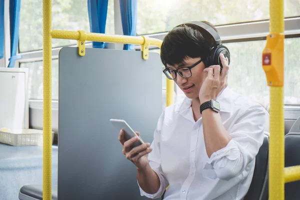 Jovem Asiático Viajante Sentado Ônibus Ouvindo Música Smartphone Enquanto Sorri — Fotografia de Stock
