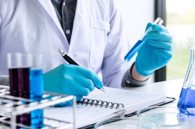 Biyokimya Laboratuvarı araştırma, kimyager örnek ve laboratuvar kaydında kimyasal sıvı içeren ekipman ve bilim deneyleri cam ürünleri ile analiz ediyor.