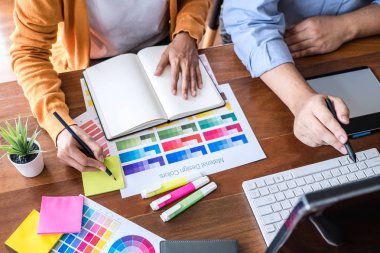 Renk seçimi ve renk örnekleri üzerinde çalışan iki iş arkadaşı yaratıcı grafik tasarımcısı, çalışma araçları ve aksesuarlarla iş yerindeki grafik tabletine çizim yapıyor.