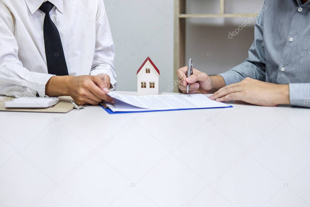 Real estate broker agent presenting and consult to customer to decision making sign insurance form agreement, home model, concerning mortgage loan offer for and house insurance.