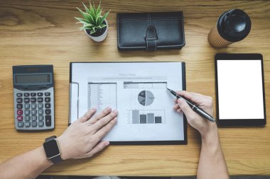 Bir grafik belge mali rapor ve analiz hesaplama maliyet ofis masası, hesap makinesiyle ve diğer nesnelerin çevresine, üstten görünüm çalışma alanı ve boş ekran tablet üzerinde çalışan iş adamı.