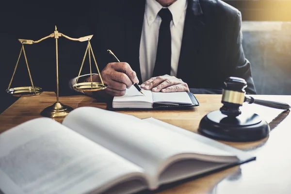 Male lawyer or judge working with contract papers, Law books and wooden gavel on table in courtroom, Justice lawyers at law firm, Law and Legal services concept.