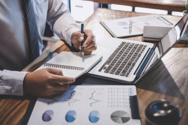 Dizüstü bilgisayarda office kullanarak bir laptop ve belge rapor, grafik ve analiz iş stratejisi geliştirme kar ile çalışan erkekler işyerinde, yazarak girişimci işadamı.