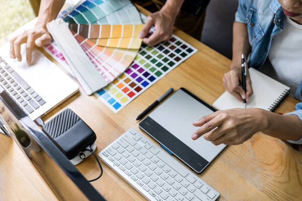 Team of young colleagues creative graphic designer working on color selection and drawing on graphics tablet at workplace, Color swatch samples chart for selection coloring.
