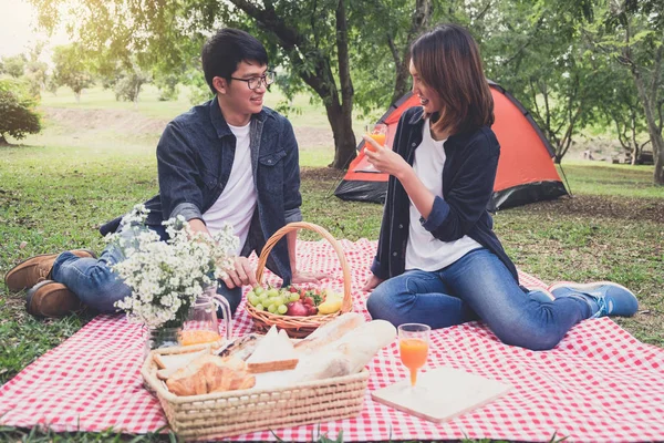 Couple in love drink a orange juice and fruits on summer picnic, leisure, holidays, eating, people and relaxation concept.