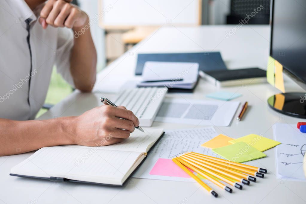 Businessman working writing making note business plan and graphic designer with computer in office.