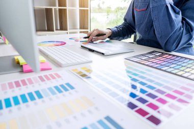 İş yerinde iş araçları ve aksesuarlarıyla renk seçimi ve grafik tableti üzerinde çalışan erkek yaratıcı grafik tasarımcı resmi.