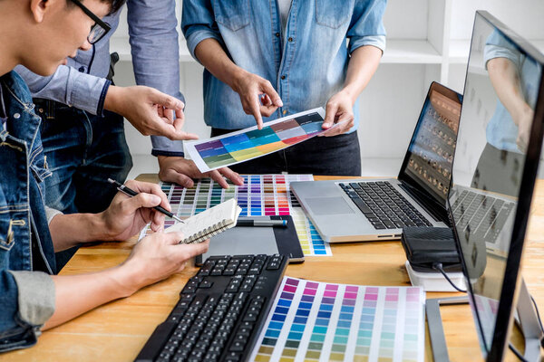 Team of young colleagues creative graphic designer working on color selection and drawing on graphics tablet at workplace, Color swatch samples chart for selection coloring.