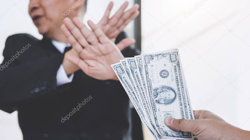 Bribery and corruption concept, Businessman refusing receive money in the envelope to agreement contract, A bribe in the form of dollar bills.