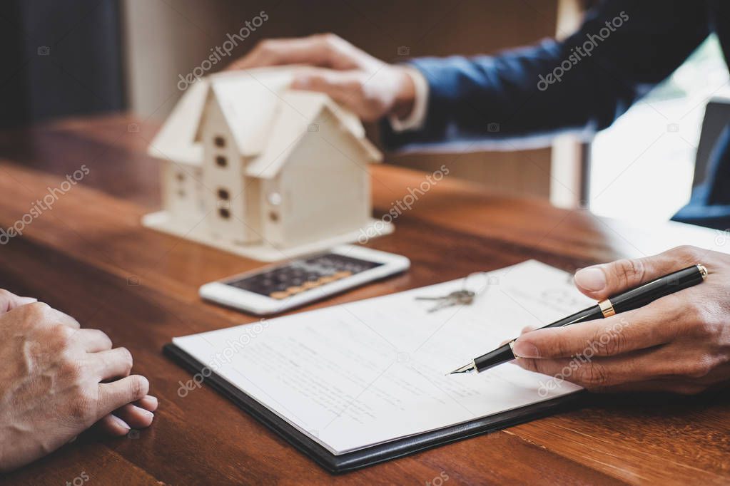 Real estate broker agent presenting and consult to customer to decision making sign insurance form agreement, home model, concerning mortgage loan offer for and house insurance.