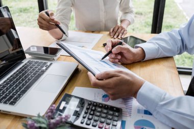 İki işletme yöneticisi yeni proje başarı istatistikleri ile tartışıyorlar, Ortaklar her iki şirket için profesyonel yatırımcılarla görüşüyor belge ile birlikte proje başlatıyorlar.
