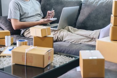 Küçük işletme parsel istemciye evde, sevkiyat için satınalma siparişi ve hazırlama paket ürün üzerinde Not ambalaj sıralama kutusu teslim online pazar ile çalışan genç girişimci KOBİ serbest adam.