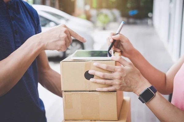 Woman customer appending signature in digital tablet and receiving a cardboard boxes parcel from delivery service courier, Home delivery service and working with service mind.