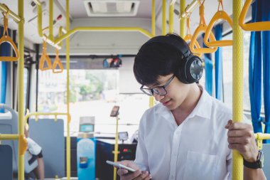 Genç Asyalı adam Gezgin üzerinde müzik otobüste ayakta